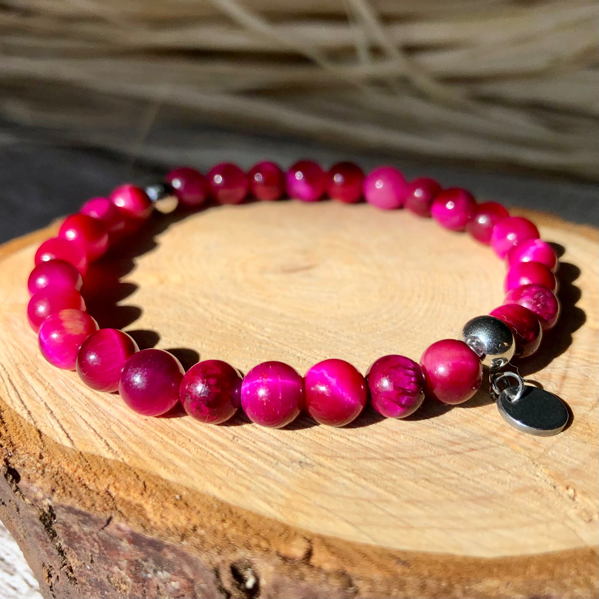 A pink dyed tiger-eye beaded bracelet with stainless steel spacers